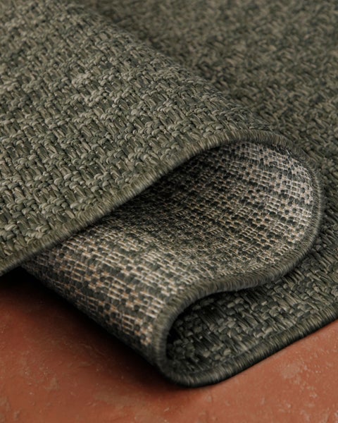 Gewebter Flachgewebe-Teppich in Sisal-Optik mit strukturierter Oberfläche und umgeschlagener Ecke.