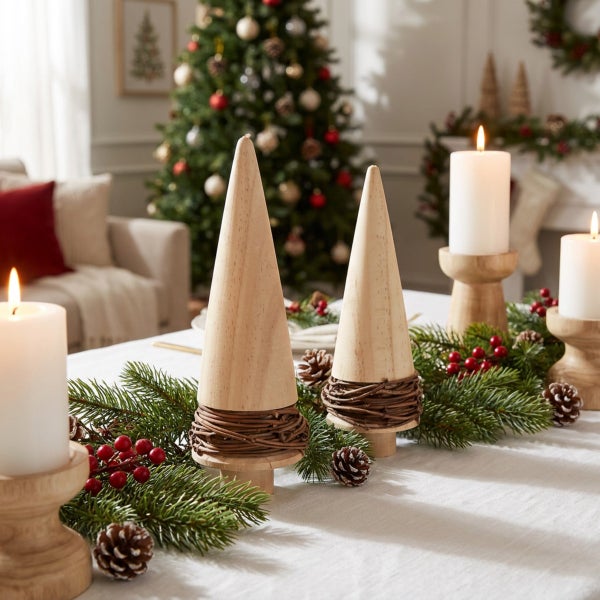Festliche Tischdekoration mit Holz-Tannenbäumen, Kerzen, Tannenzweigen, Beeren und Zapfen in einem weihnachtlich geschmückten Wohnzimmer.