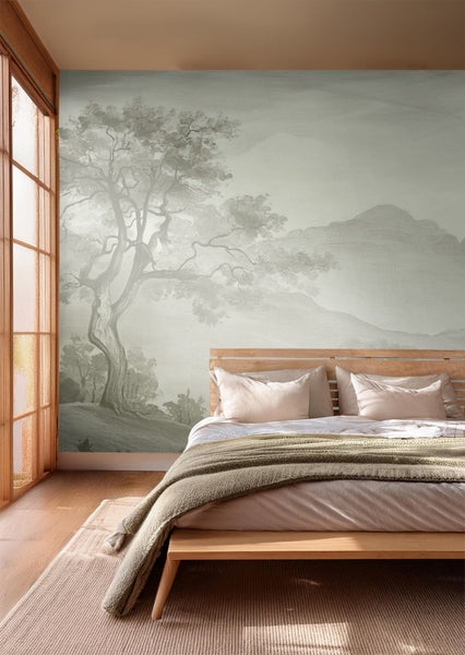 Schlafzimmer mit gemusterter Tapete mit Baum- und Bergmotiv hinter einem Holzbett