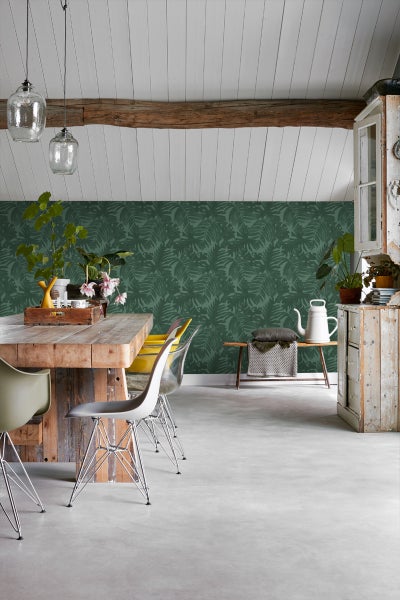 Heller Raum mit Holztisch, Stühlen, Pflanzendekoration und Wandtapete mit Blattmuster