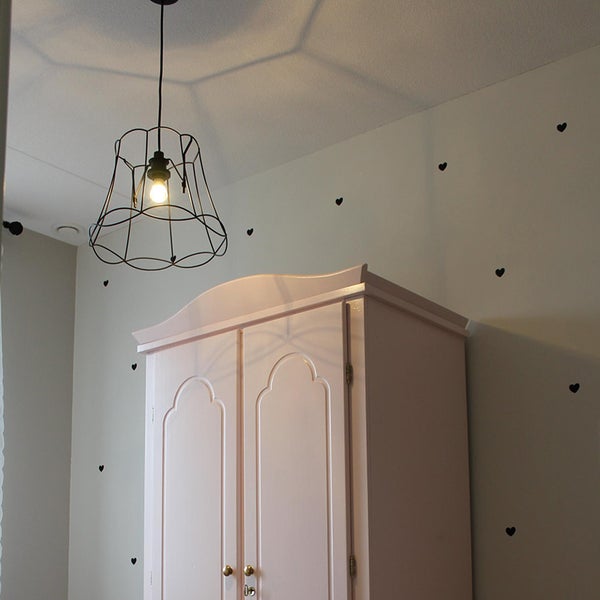 Zimmer mit einer Pendelleuchte aus Metalldraht und einem Kleiderschrank