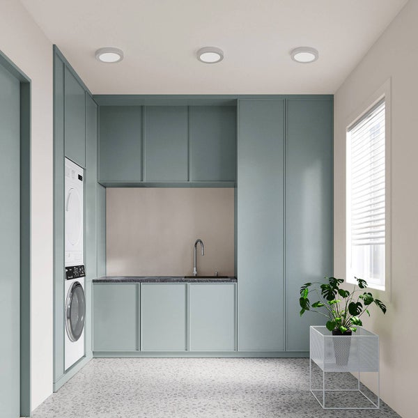 Moderner Hauswirtschaftsraum mit Einbauschränken, Waschmaschine, Trockner, kleinem Spülbecken und Terrazzoboden.