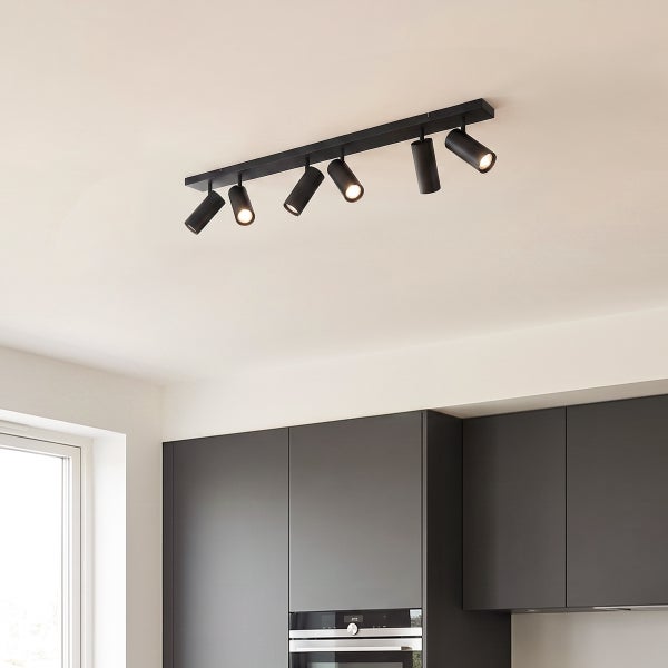 Moderne Deckenleuchte mit sechs verstellbaren Strahlern montiert an einer langen Leistenschiene in einer minimalistisch gestalteten Küche.