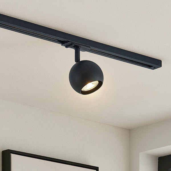 Schwarzer kugelförmiger Spot an einer schwarzen Stromschiene montiert an der Decke.