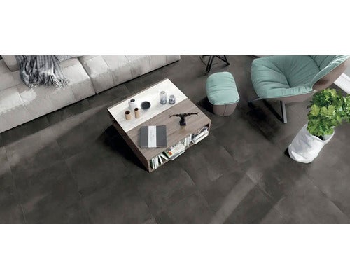 Draufsicht eines Wohnzimmers mit dunklen Bodenfliesen, Sofa, Couchtisch und Sessel in einer modernen Einrichtung.