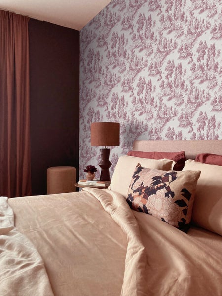 Vliestapete mit Toile-de-Jouy-Muster in einem Schlafzimmer mit Bett, Nachttischlampe und dunkler Akzentwand.