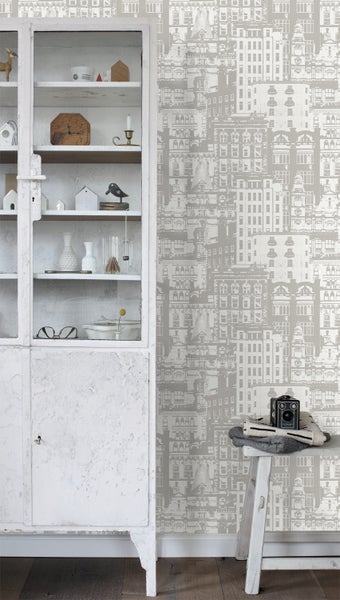 Szene mit einem weißen Schrank, einer Bank mit einer Kamera und einer Tapete mit Gebäudemotiv