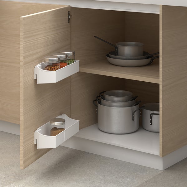 Offener Küchenunterschrank mit zwei an der Tür montierten weißen Aufbewahrungsboxen für Gewürze und Töpfen im Schrankinneren.