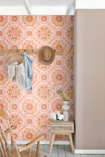 Dekorativer Raum mit gemusterter Tapete, Holzgarderobe, geflochtenem Korb, Jacke, Hut, Beistelltisch mit Blumen und Stuhl