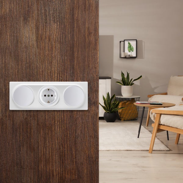 Eine dreifache Steckdosenkombination mit Schutzkontakt-Steckdose, montiert an einer holzfarbenen Wand in einem wohnlich eingerichteten Zimmer.