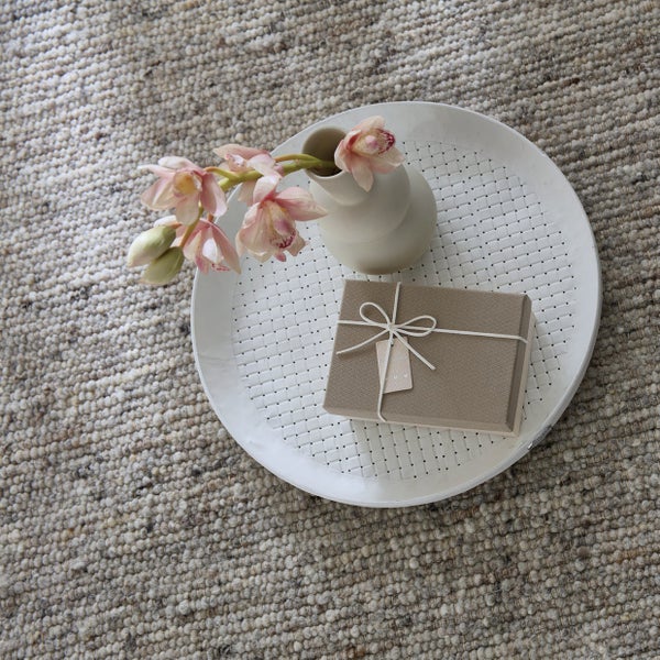 Dekoration mit Geschenk, Blumen in Vase und Tablett auf einem Teppich