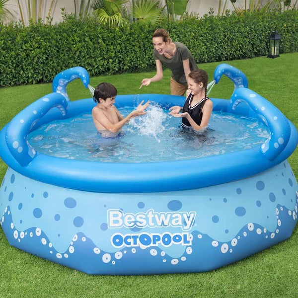 Blaues Bestway Octopool Planschbecken im Garten mit wassersprühenden Tentakeln. Kinder spielen im Pool, eine Frau schaut zu.