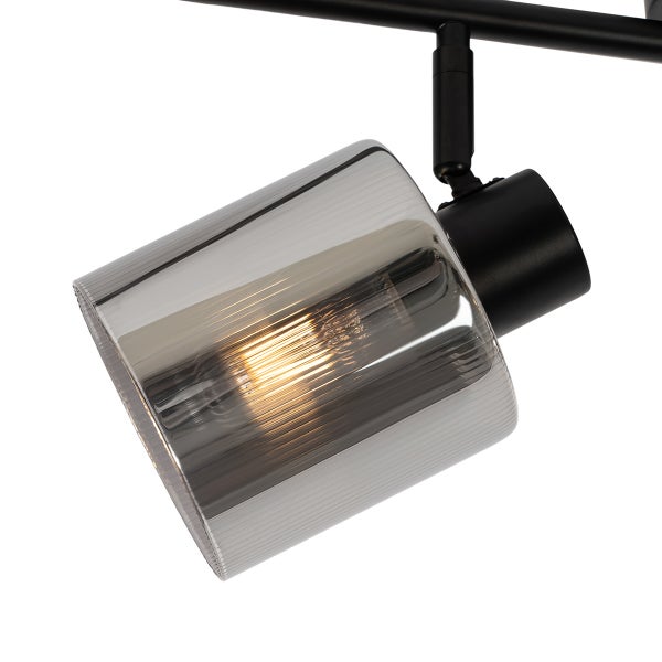 Strahler aus schwarzem Metall mit geriffeltem Schirm aus Rauchglas und eingeschaltetem Leuchtmittel.