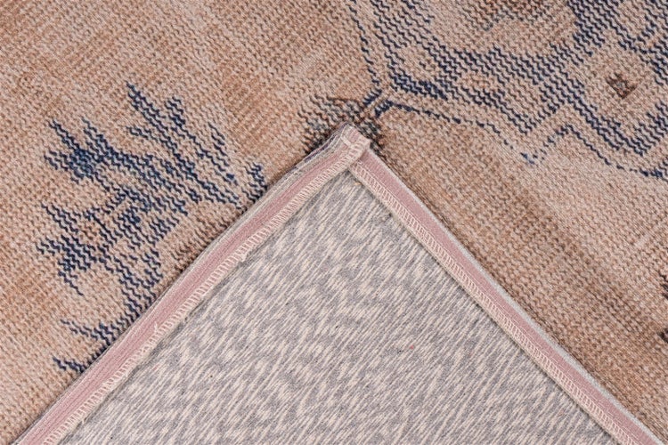 Nahaufnahme eines gewebten Teppichs mit orientalischem Muster und umgeschlagener Ecke zur Ansicht der Rückseite.