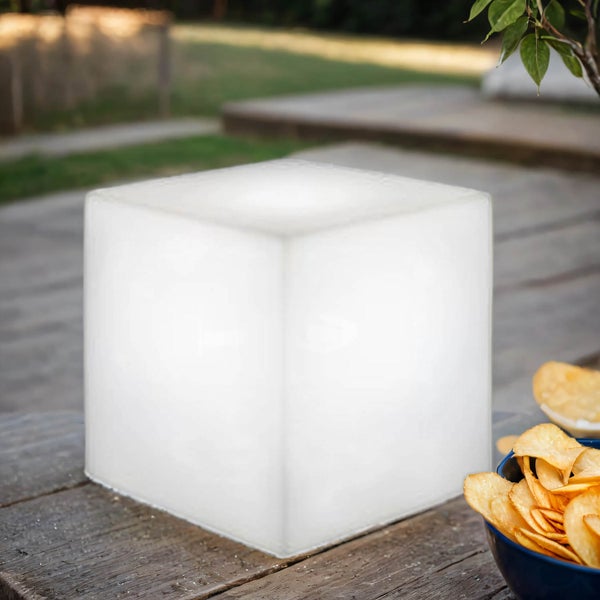 Leuchtender LED Würfel als Außenleuchte aus Kunststoff auf einem Holztisch