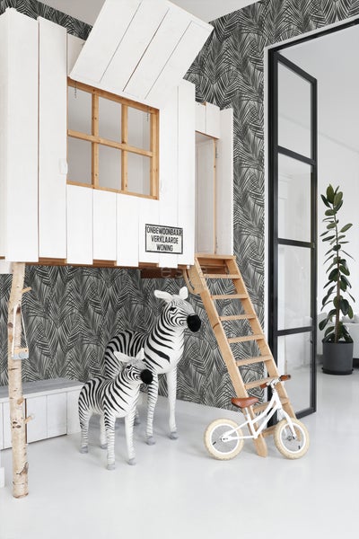 Kinderzimmer mit Baumhaus, Zebras und Laufrad vor einer Tapete mit Palmenmuster