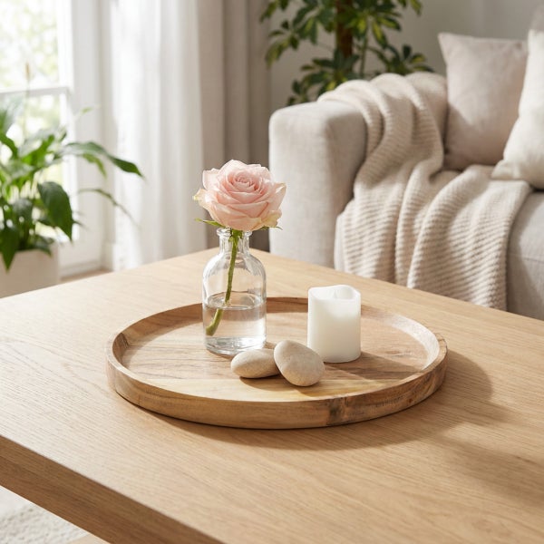 Rundes Holztablett als Dekoration auf einem Wohnzimmertisch mit einer Glasvase, einer Rose, einer LED Kerze und zwei Dekosteinen.