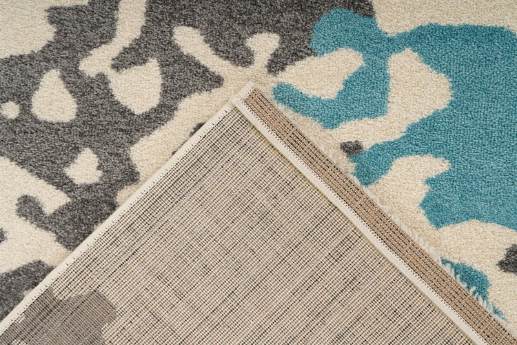 Kurzflor-Teppich mit abstraktem Muster in Grau, Türkis und Beige sowie strukturierter Rückseite.