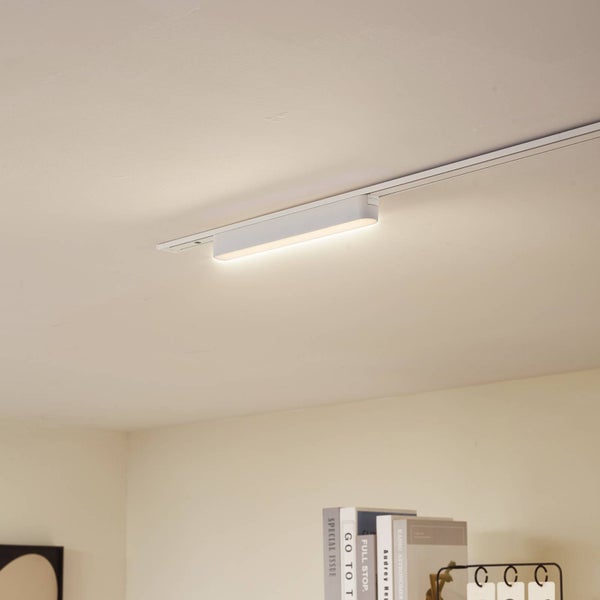 Weiße, längliche LED-Schienenleuchte an einer Decken-Stromschiene, leuchtet in warmweißem Licht.