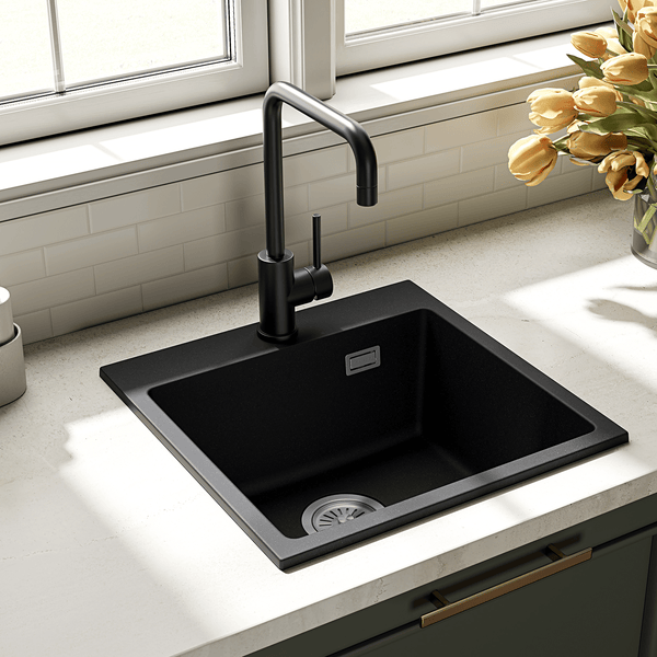 Moderne schwarze Küchenspüle aus Verbundwerkstoff mit einer hohen schwarzen Einhebelmischbatterie in einer hellen Küchenzeile mit Fenster.