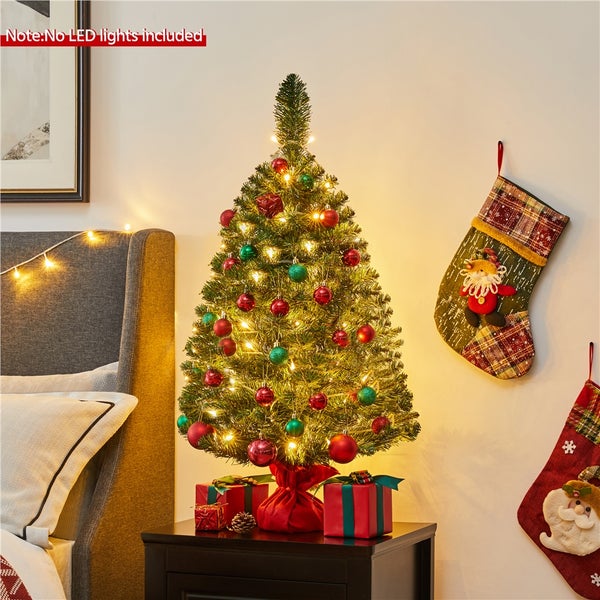 Dekorierter Weihnachtsbaum mit Christbaumkugeln und Geschenken auf einem Nachttisch