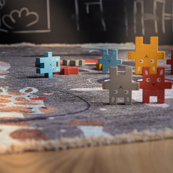 Kinderspielteppich mit Tiermotiven und darauf platzierten bunten Holzfiguren in Hasenform