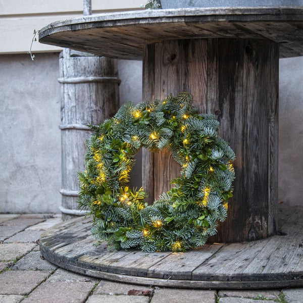 Geschmückter Adventskranz mit Lichtern auf einem Holztisch