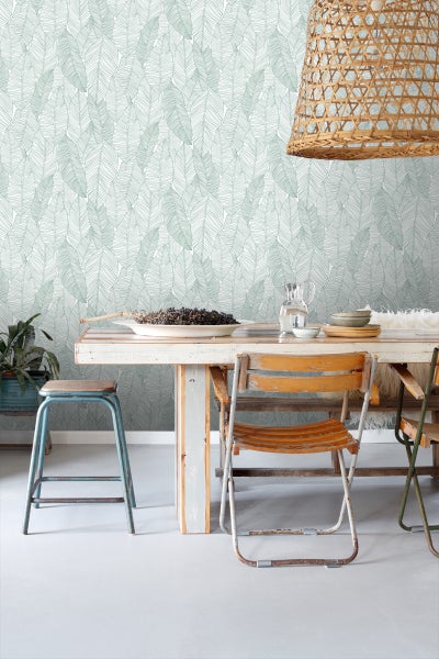 Heller Raum mit Blättermuster-Tapete, Holztisch und Rattanhängelampe