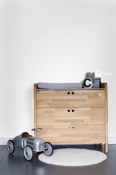 Helles Kinderzimmer mit Holzkommode, Spielzeugauto und rundem Teppich