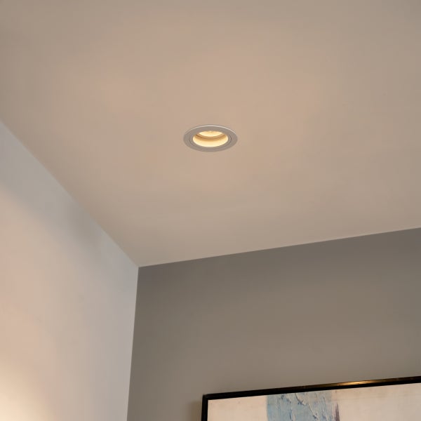 Runder LED-Einbaustrahler in einer Decke mit warmweißem Lichtschein.