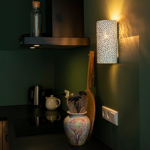 Küchenszene mit Dunstabzugshaube, Küchenutensilien und beleuchteter Wandleuchte