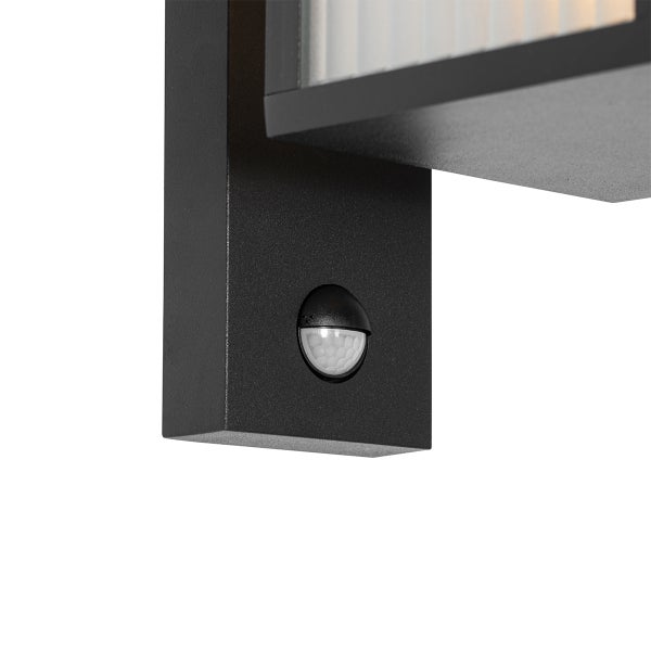 Detailaufnahme eines Bewegungsmelders an einer schwarzen Außenwandleuchte.