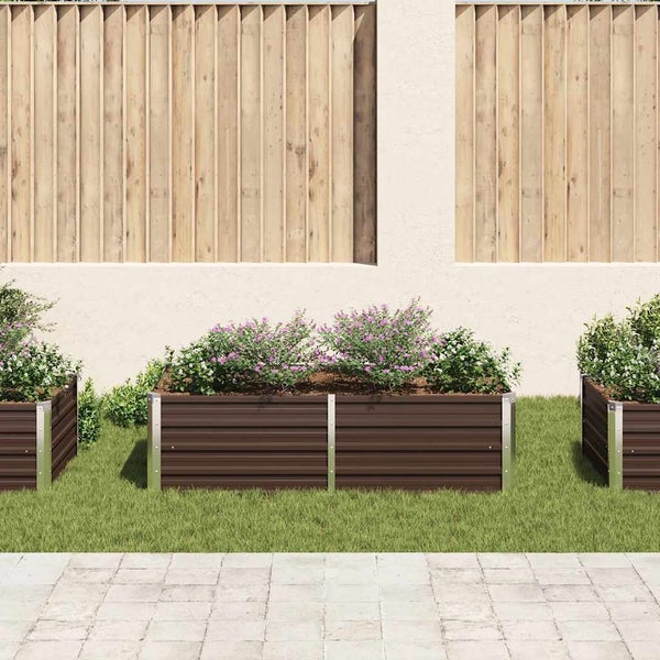 Bepflanztes Hochbeet aus gewelltem Metall mit Eckprofilen im Garten vor einer Holzwand auf einer Rasenfläche.