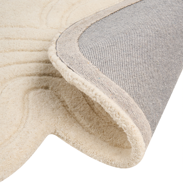 Nahaufnahme eines Hochflor-Teppichs mit gewellter Struktur und sichtbarer gewebter Rückseite.