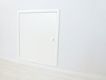 Quadratische Revisionsklappe in einer Wand montiert mit einem kleinen Drehverschluss.