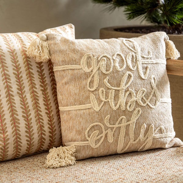 Dekorative Kissen mit Quasten und Schriftzug auf einem Sofa