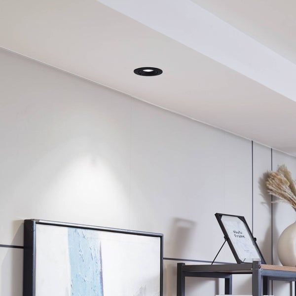 Schwarzer LED-Einbaustrahler in einer weißen Decke, der Licht auf ein Wandbild wirft.
