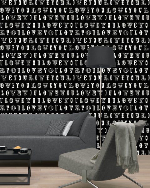 Wohnzimmer mit Sofa, Sessel, Stehlampe und Tapete mit dem Schriftzug Ich liebe dich.