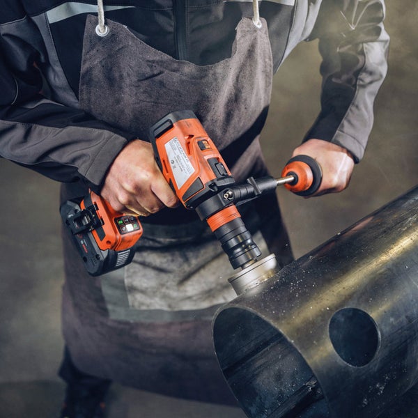 Handwerker mit Akku-Bohrschrauber beim Bohren eines Metallrohrs