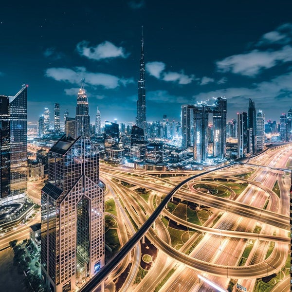 Nachtaufnahme der Skyline von Dubai mit dem Burj Khalifa und beleuchteten Straßen