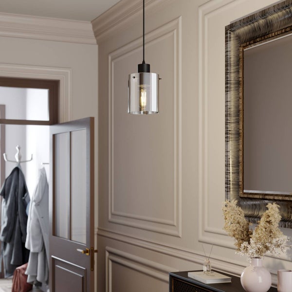 Pendelleuchte mit zylindrischem Glasschirm in einem Raum mit Wandzierleisten, einem großen Spiegel und einer Anrichte mit Dekoration.