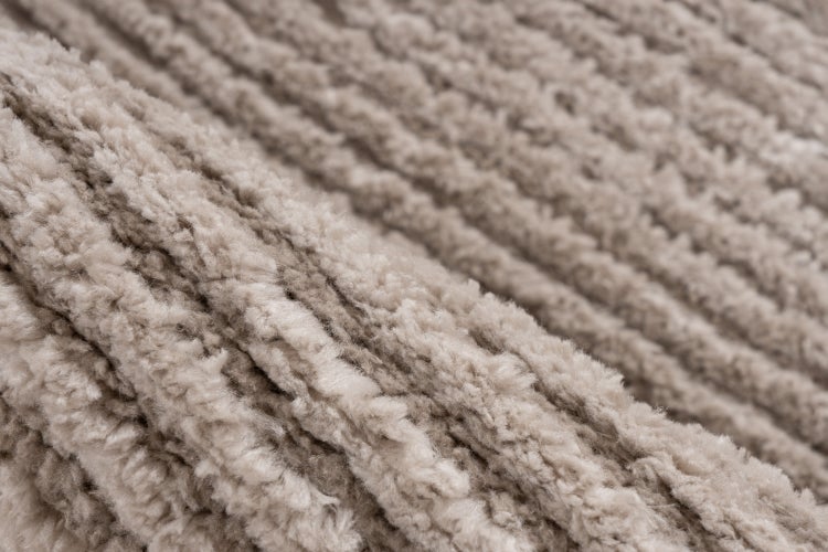 Nahaufnahme der Textur eines weichen Hochflor Teppichs mit gestreiften Fasern