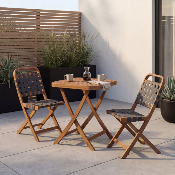 Gartenset aus Holz mit quadratischem Klapptisch und zwei Klappstühlen mit geflochtener Sitzfläche auf einer modernen Terrasse.