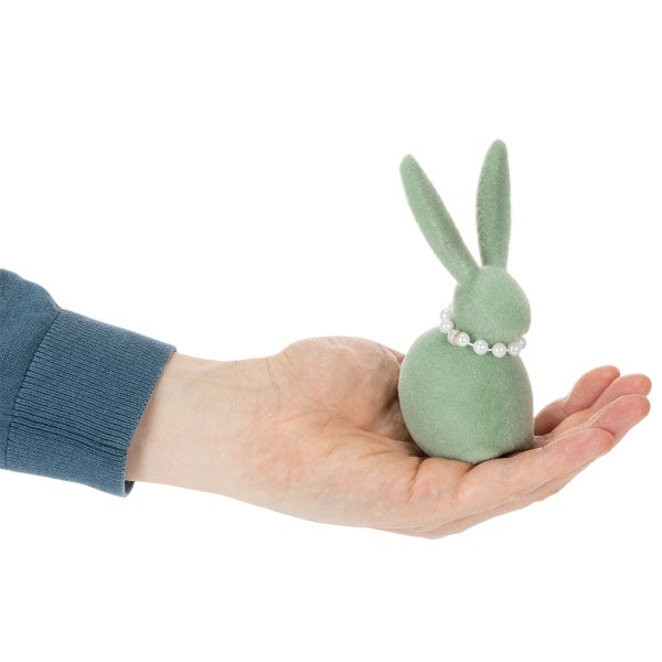 Dekorativer Osterhase mit Perlenkette in einer Hand