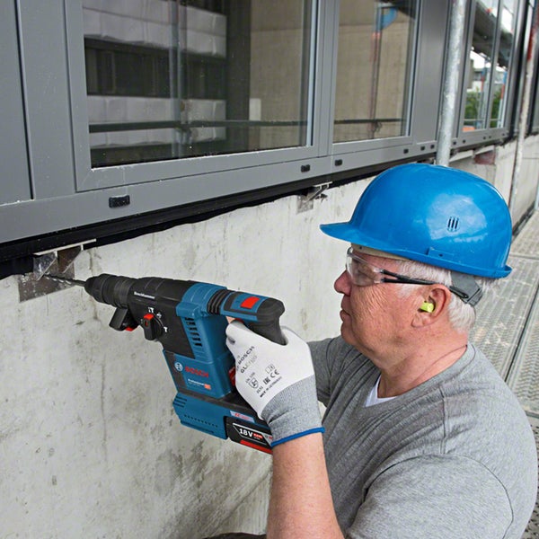 Ein Arbeiter bohrt mit einem Bohrhammer in eine Betonwand