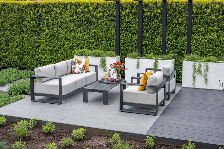 Modernes Garten-Lounge-Set aus Aluminium mit einem Dreisitzer-Sofa, zwei Sesseln und einem Couchtisch auf einer Terrasse mit Fliesen und Holzdielen.
