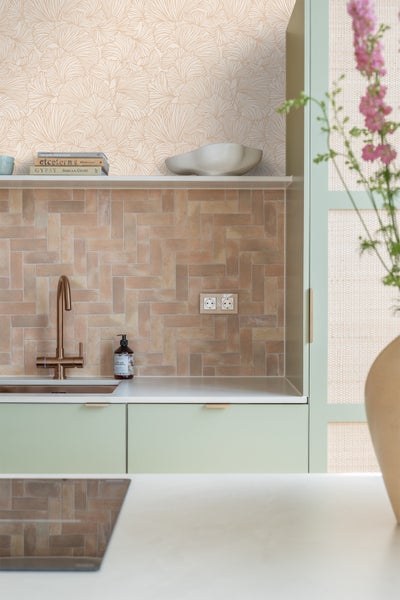 Küchenszene mit Spüle, Armatur, Fliesenwand und floraler Tapete