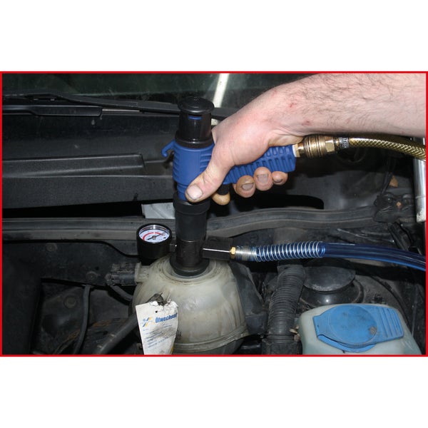 Hand der einen Druckluft Ölabsaugpumpe an einem Ausgleichsbehälter im Motorraum eines Autos ansetzt um Öl zu wechseln.