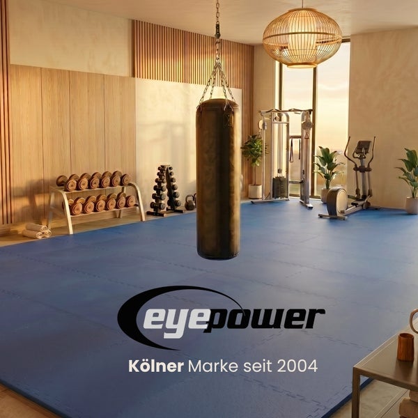 Moderner Fitnessraum mit blauen Bodenschutzmatten, Boxsack, Hantelstation, Trainingsgeräten und eyepower Logo.