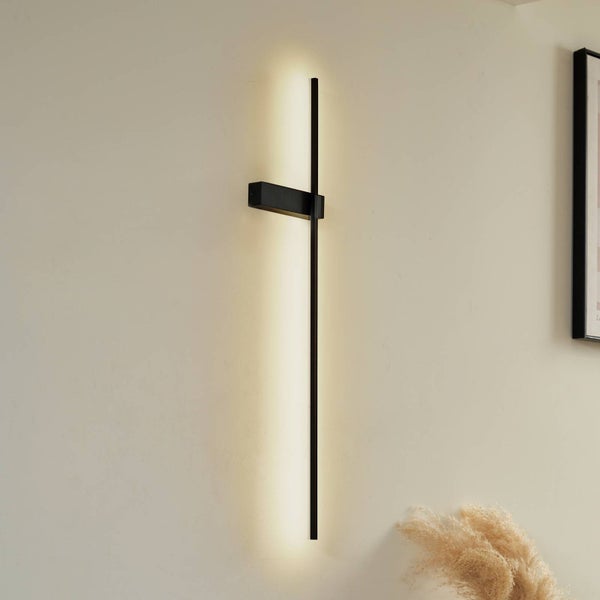 Moderne schwarze LED-Wandleuchte in minimalistischem Stab-Design mit indirekter Beleuchtung an einer hellen Wand.